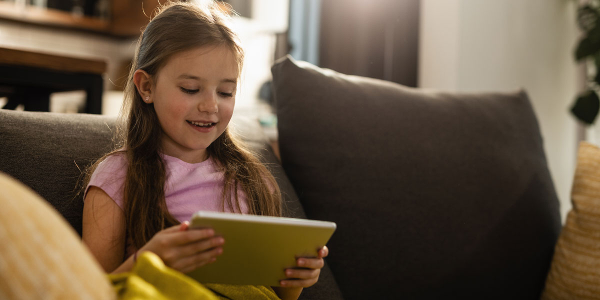 Little girl looking at tablet on a sofa