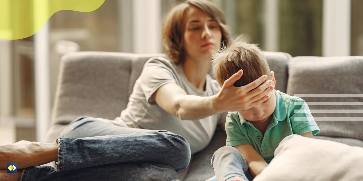 Mother smiling at child on sofa while child is watching TV