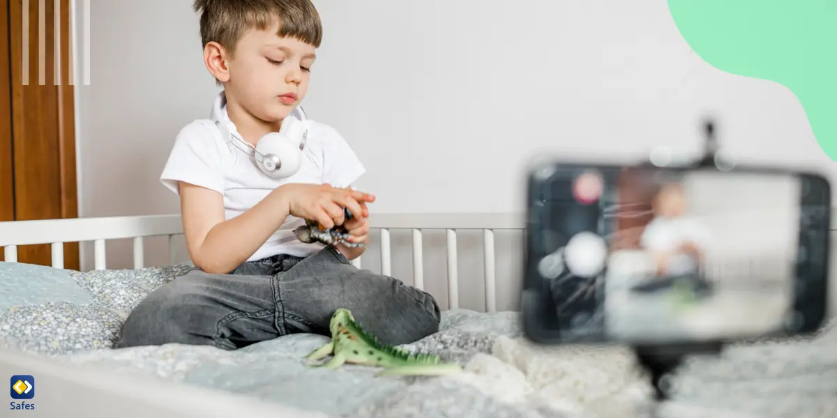 A boy playing with toys on his bed being recorded.