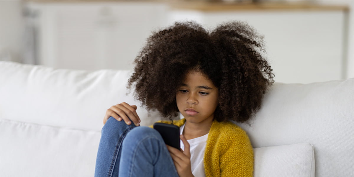 Young girl sitting on couch looking at phone