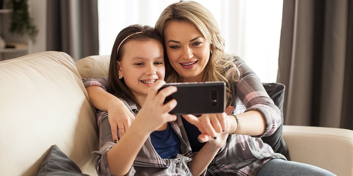 young mother and her daughter are using a smartphone