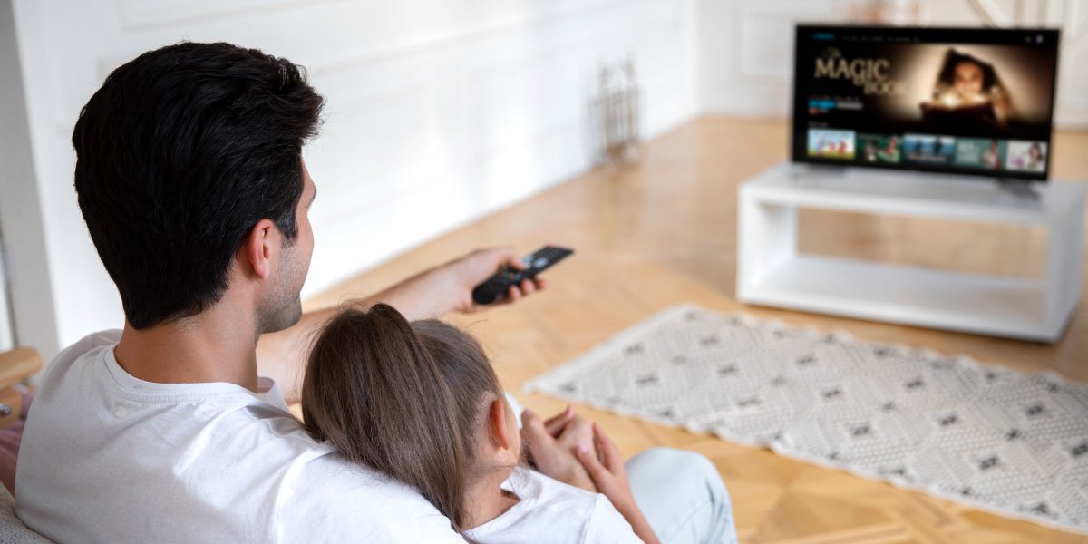 A father and his daughter watch The Magic Book on their TV