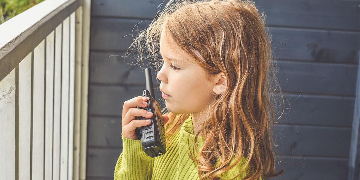 A little girl is talking into a walkie-talkie