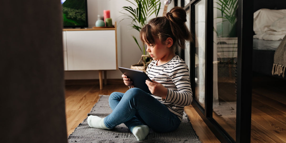 Young girl sitting on the floor using a tablet that's connected to the internet