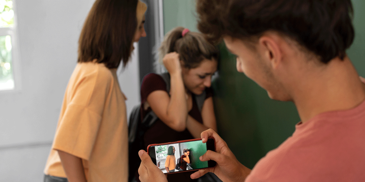 Cyberbullying harms children's mental health. A boy makes a video of a girl bullying another girl