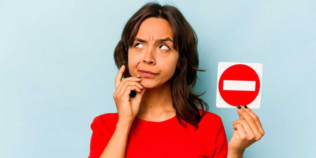 A woman holding a ban sign in her hand, wondering how to restrict apps on her child’s iPhone