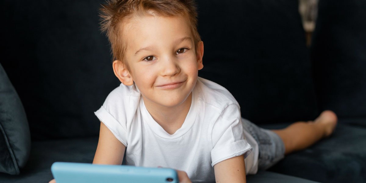 a boy in a white shirt on the couch playing Clash Royale