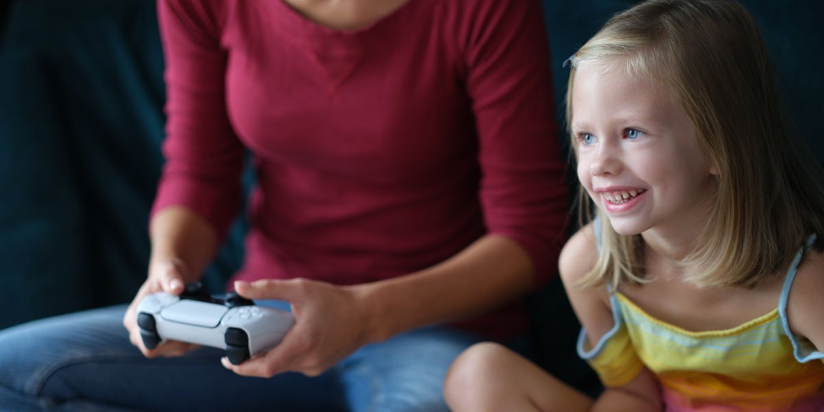 a girl in a yellow dress is playing a video game with her mother