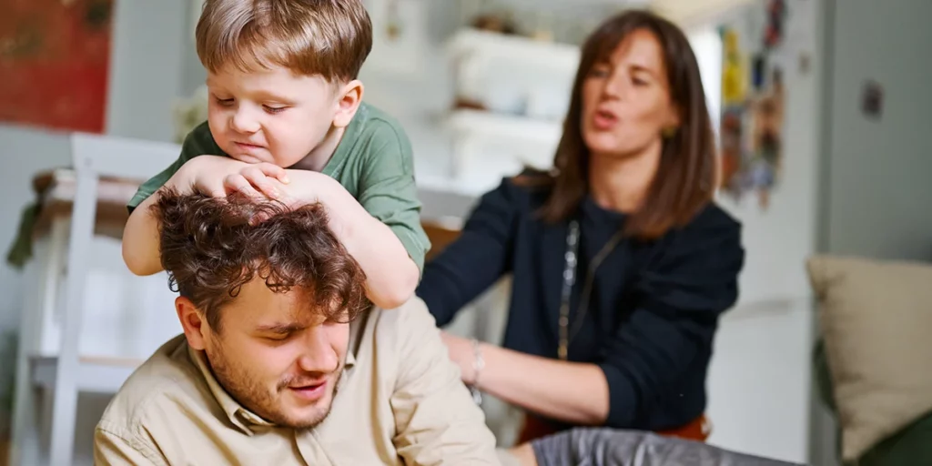 Verwöhntes Kind, das über seinen verwöhnenden Vater läuft