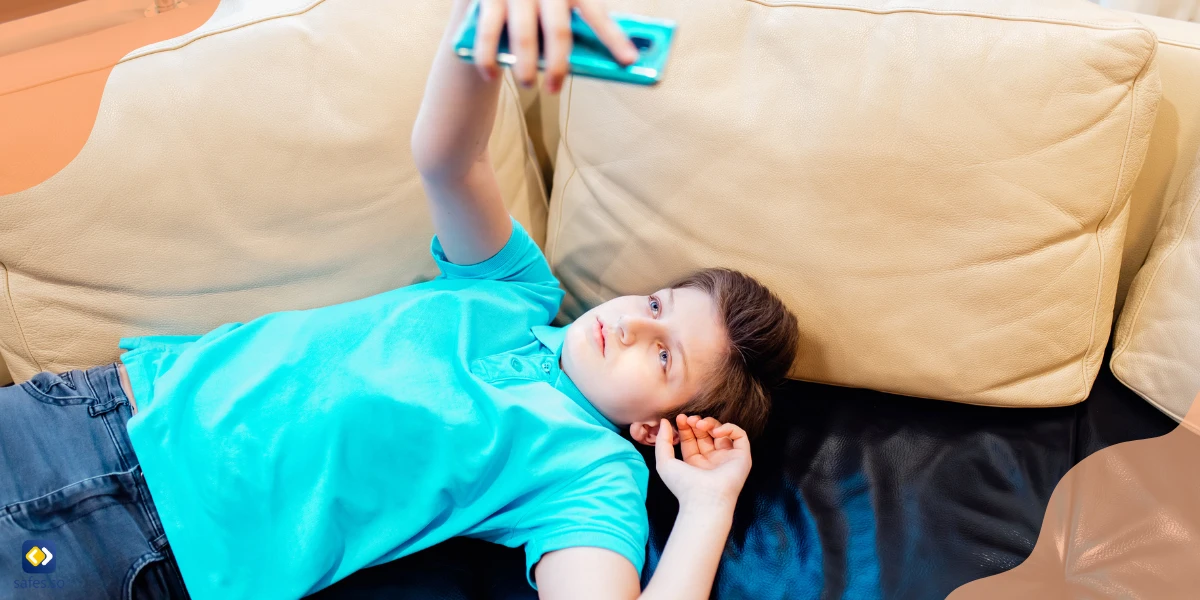 Kid lying on a couch using a phone