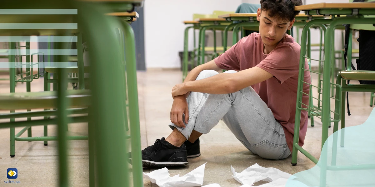 Student with low self-esteem sitting sadly on the ground