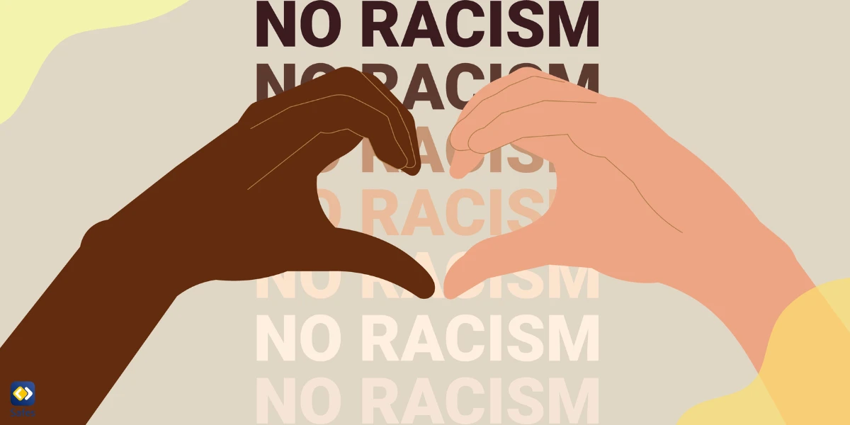 An illustration of two hands of different colors forming a heart shape over a background of “No Racism”