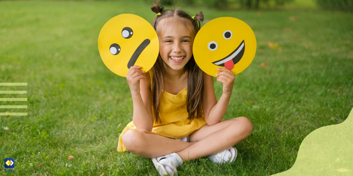 a cheerful baby girl holds 2 emotions in her hands