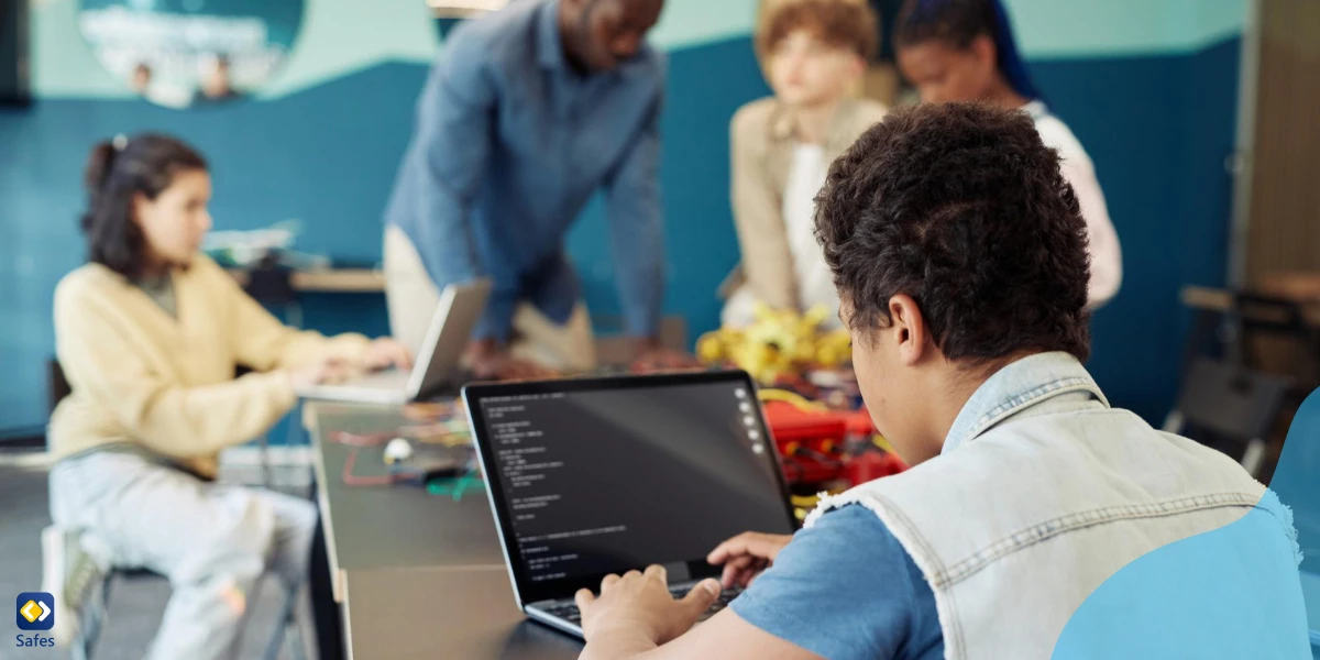 Students using their computers at school with their teacher teaching them about cyber security