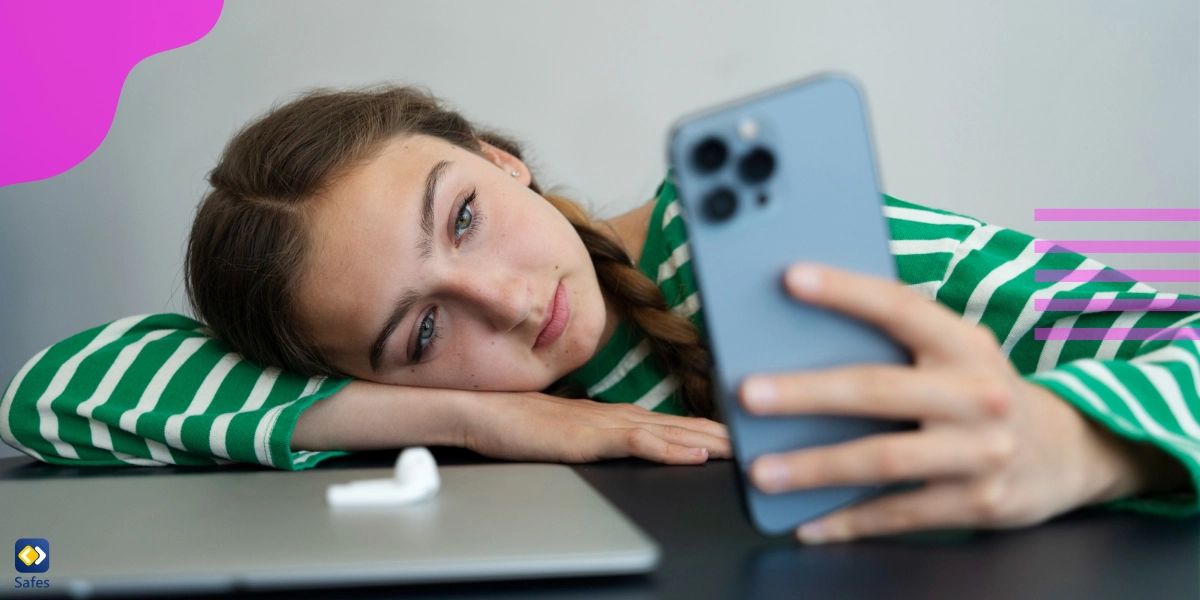 Teenagermädchen liegt mit dem Kopf auf dem Tisch und schaut sich die sozialen Medien an