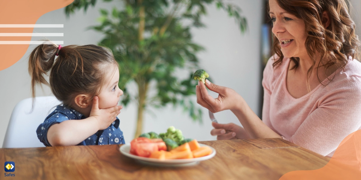 A mom is giving her daughter vegetables