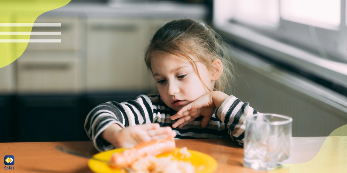 A little girl is refusing to eat food by pushing her dish