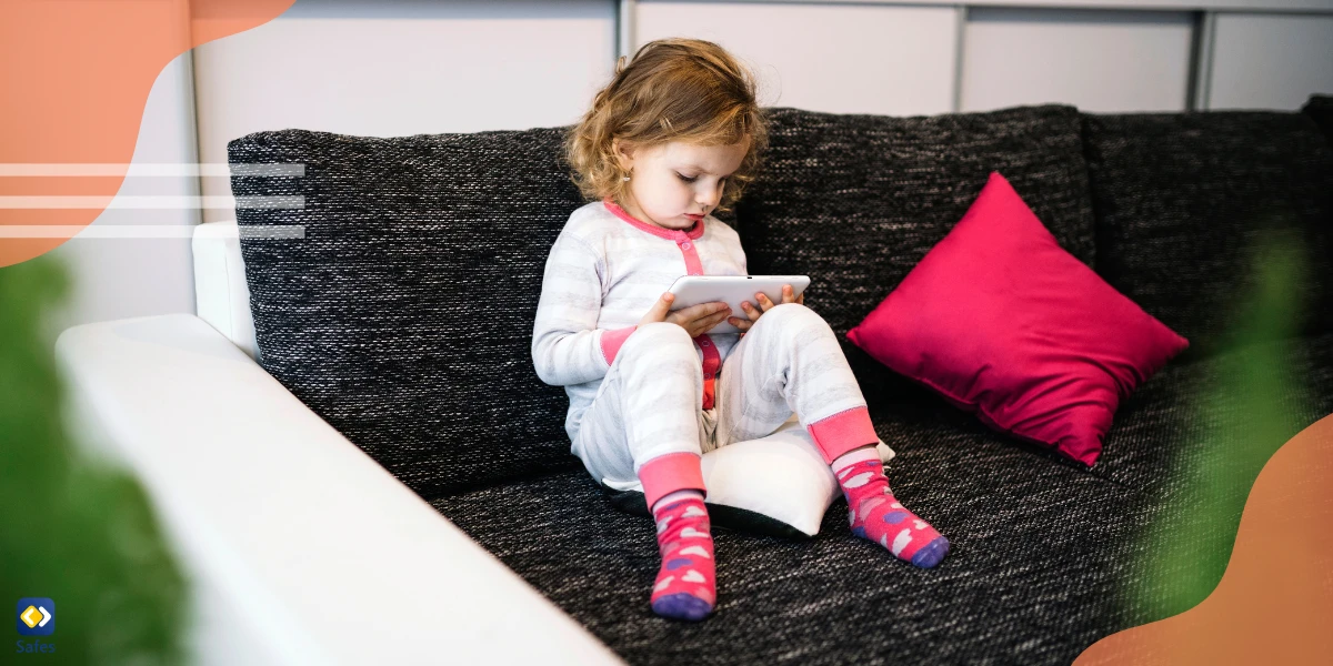 a little girl is using a tablet on the sofa