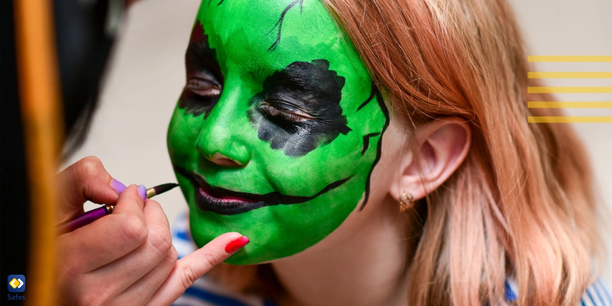 Mother painting a monster make-up on her daughter’s face