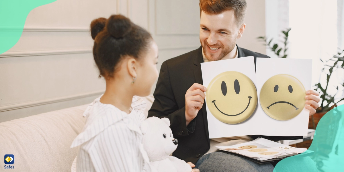 A father is showing her daughter smilies of different emotions, teaching her how to manage her emotions.