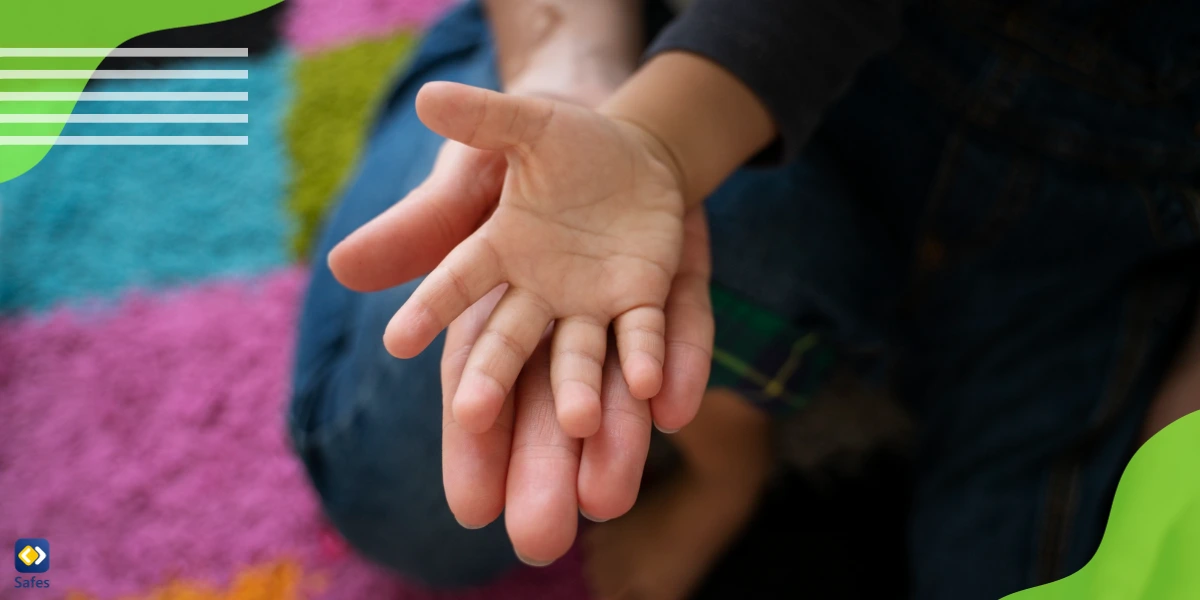 A child’s hand within an adult’s hand symbolizing the child being adopted by a family member