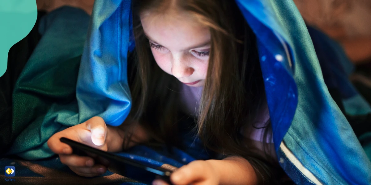 A young girl reading a book on her phone in her bed. Her parents used Safes to give her access to digital books, even in bed.