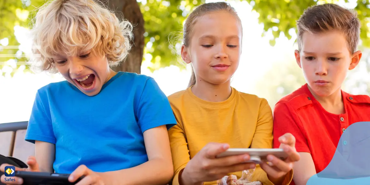 zwei Jungen und ein Mädchen, die in ihrer Freizeit in der Schule mit ihren Handys spielen