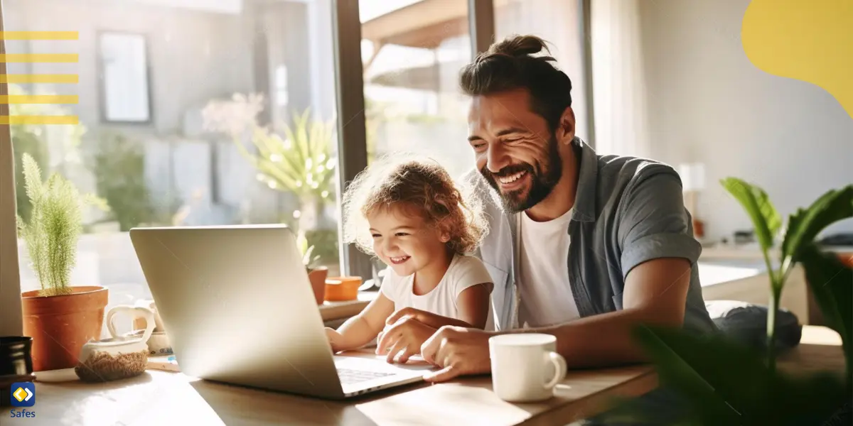 Joyful dad and daughter bond over a laptop, laughing together at the table.