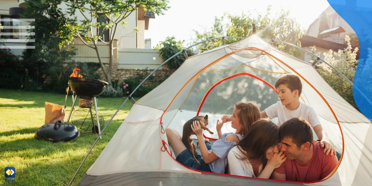 Eine Familie, die in ihrem Garten zeltet, indem sie ein Zelt und einen Grill aufstellt