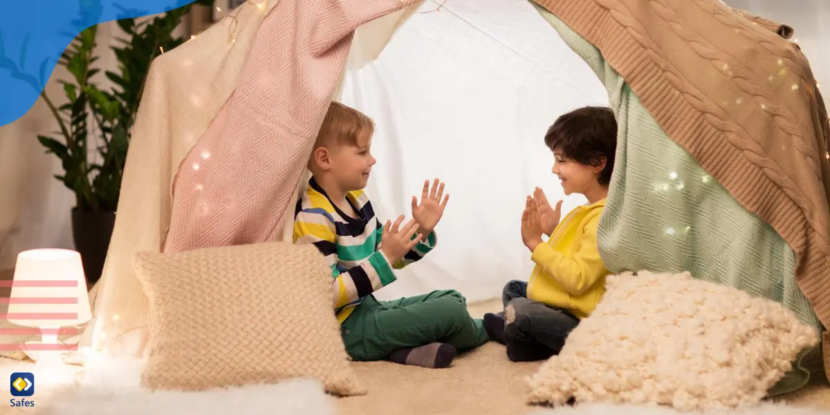 Zwei Kinder spielen zusammen in der Festung, die sie mit Laken und Kissen gebaut haben