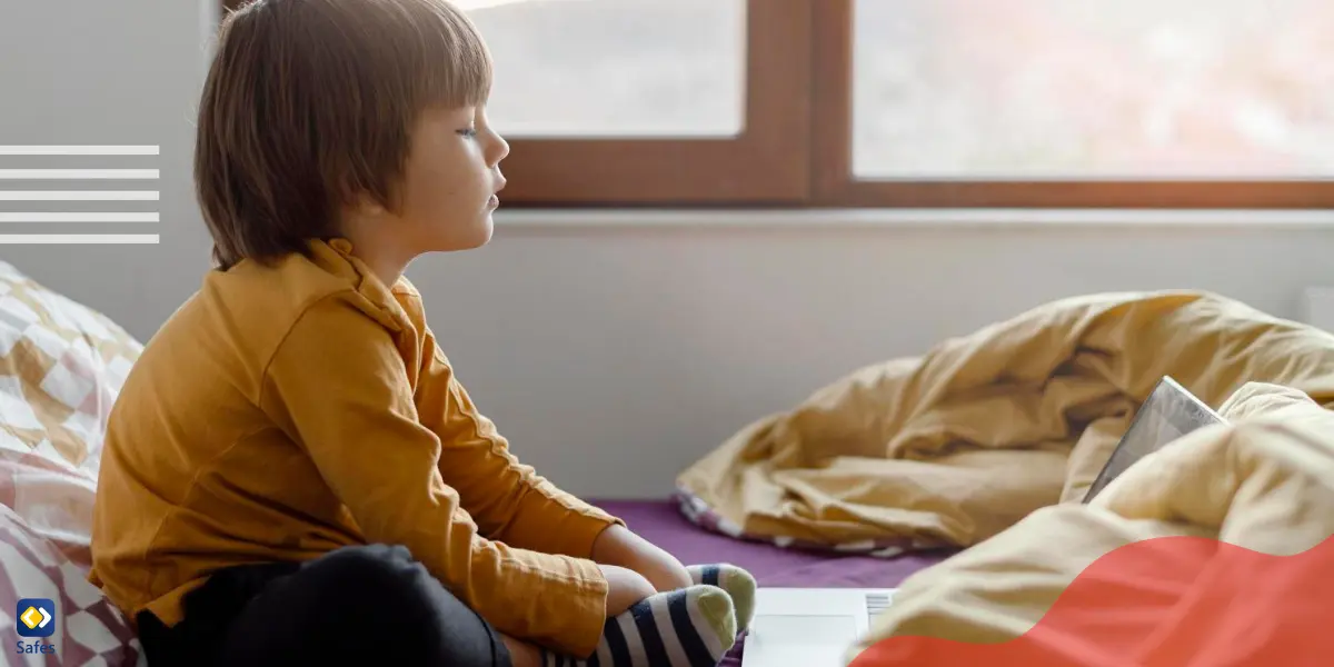 a young boy is alone at home and watching something on his laptop to entertain himself