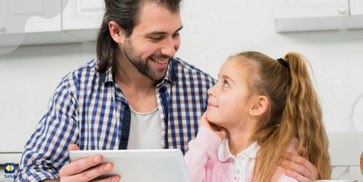 Father and daughter using a tablet together, openly communicating about screen time and online safety.