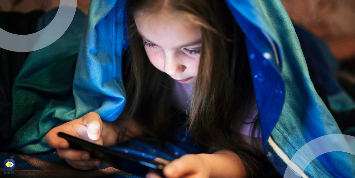 Young girl wrapped in a blanket using a smartphone.