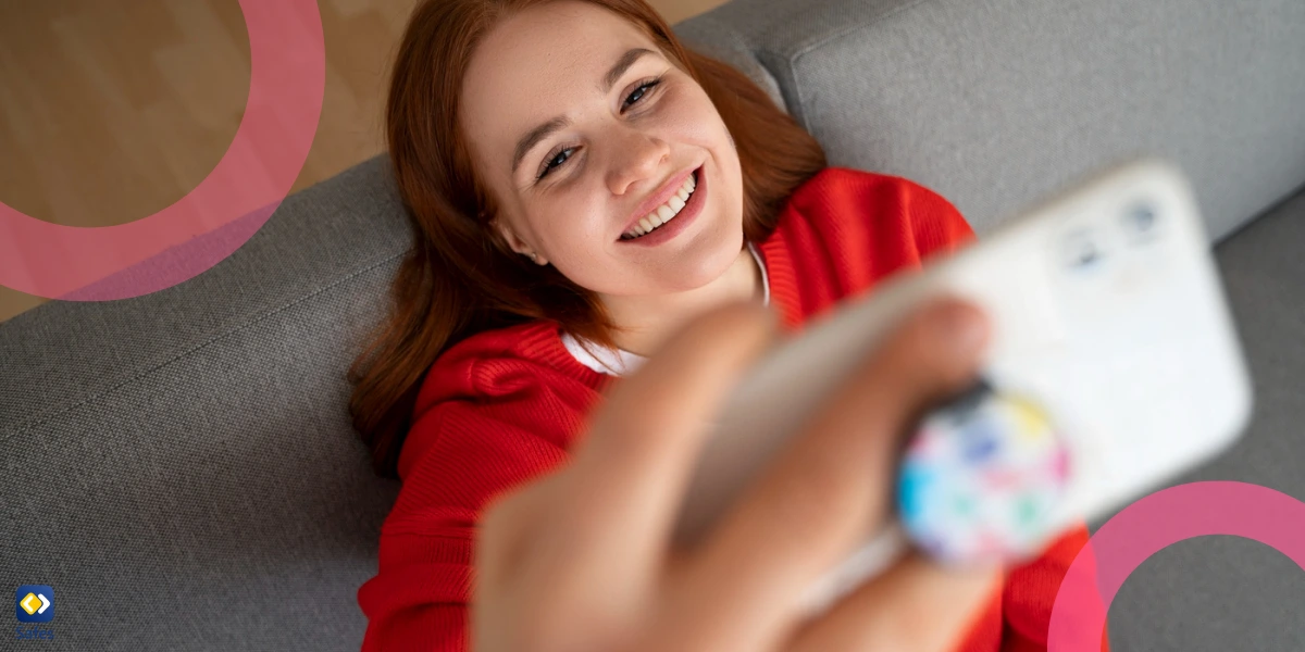 a teen girl using her smartphone at home on a couch to take a selfie of herself.