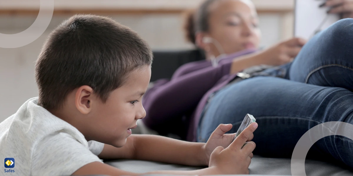 a young boy is using his phone while her mother is checking his online activities using her phone