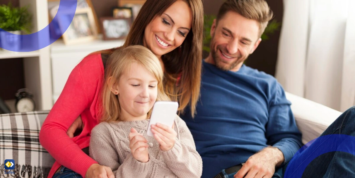 Eine dreiköpfige Familie sitzt auf einem Sofa und versammelt sich eng um ein Smartphone, das das Kind benutzt.