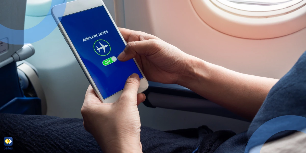 a person holding a smartphone and turning on airplane mode on a screen near the window on the airplane.