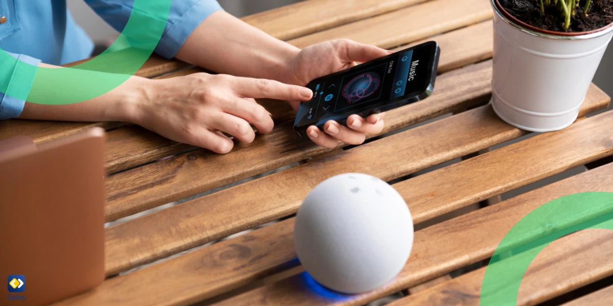 Close-up of hands holding a smartphone displaying a music app, with an Amazon Echo device positioned nearby on a table