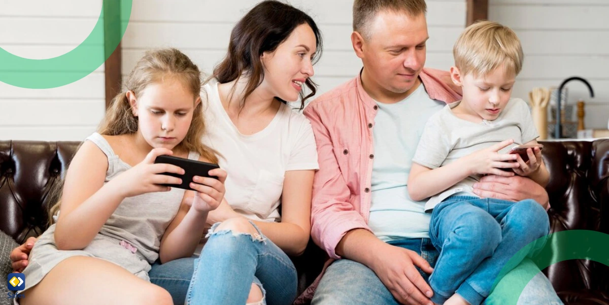 Eine Familie sitzt auf einer Couch und Eltern überprüfen, wie ihre Kinder ihre Telefone benutzen.