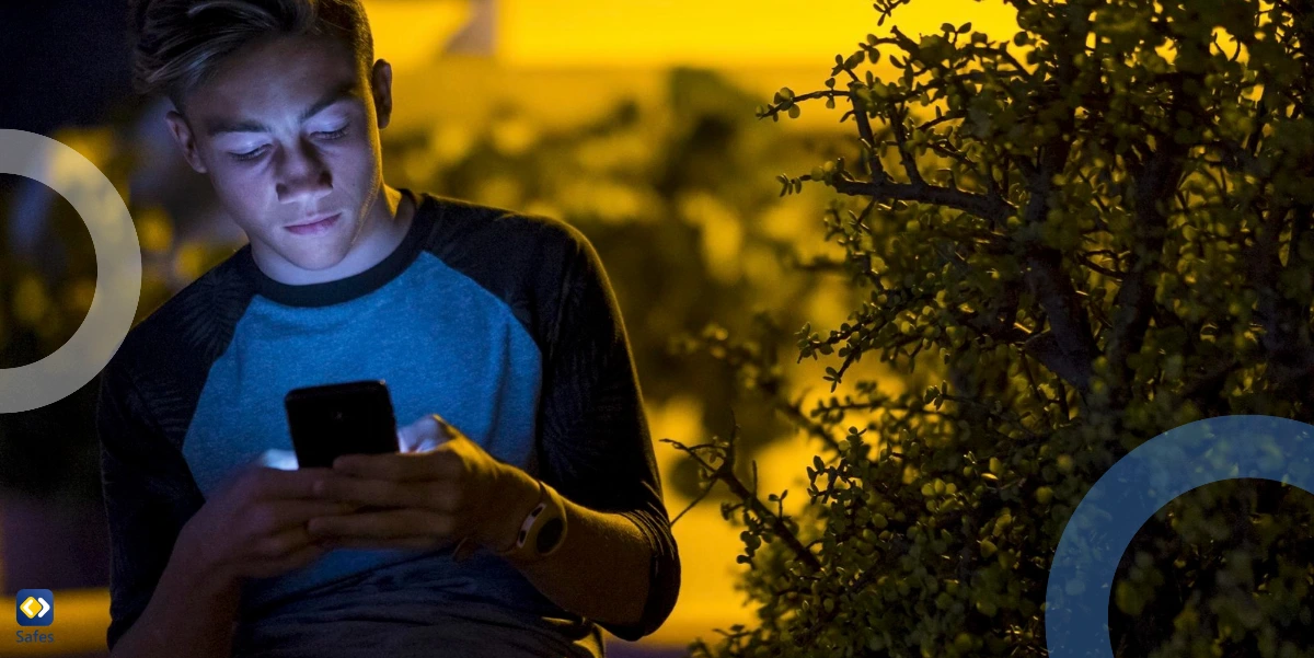 Teenager using phone outdoors at night