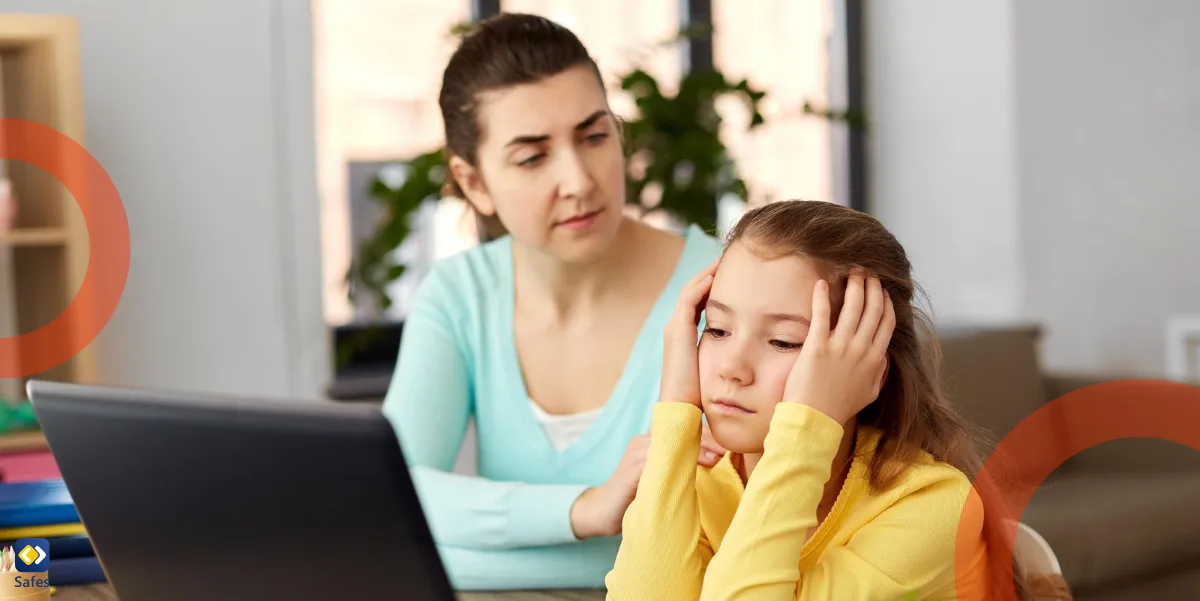 upset mother and daughter sitting at a desk with laptop.