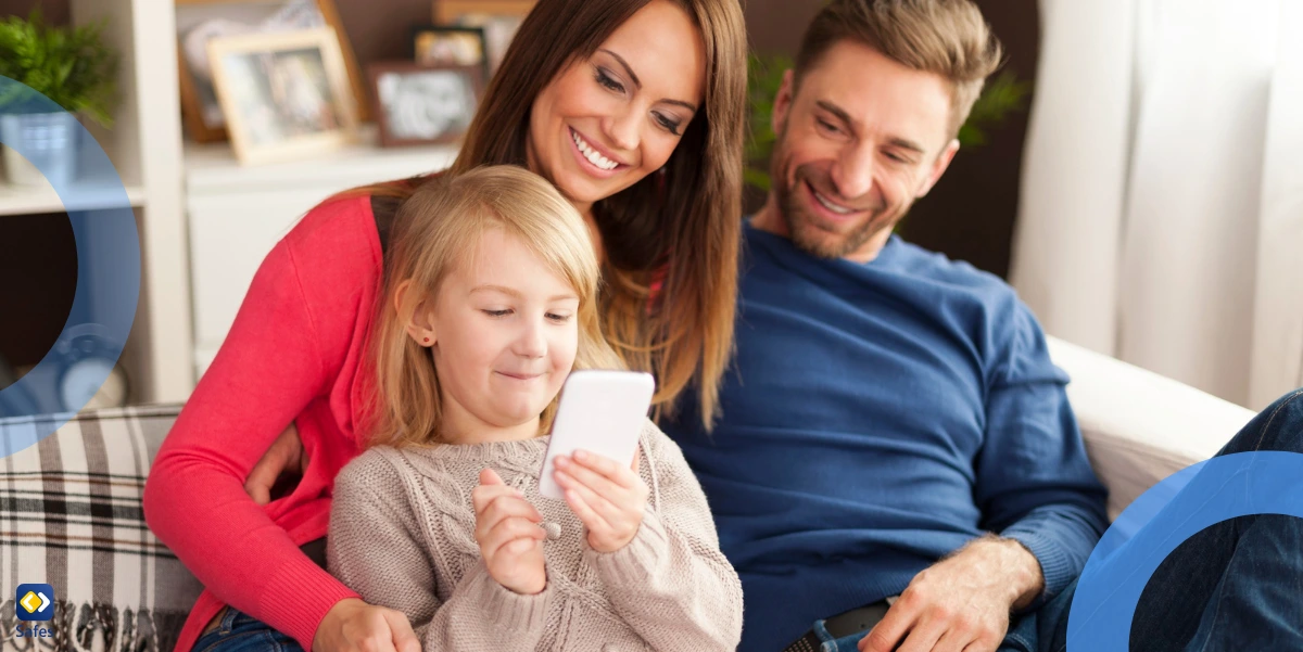 happy little girl using her phone with parents while sitting on the couch